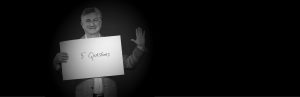 Adam Leipzig holding a sign that says 5 question